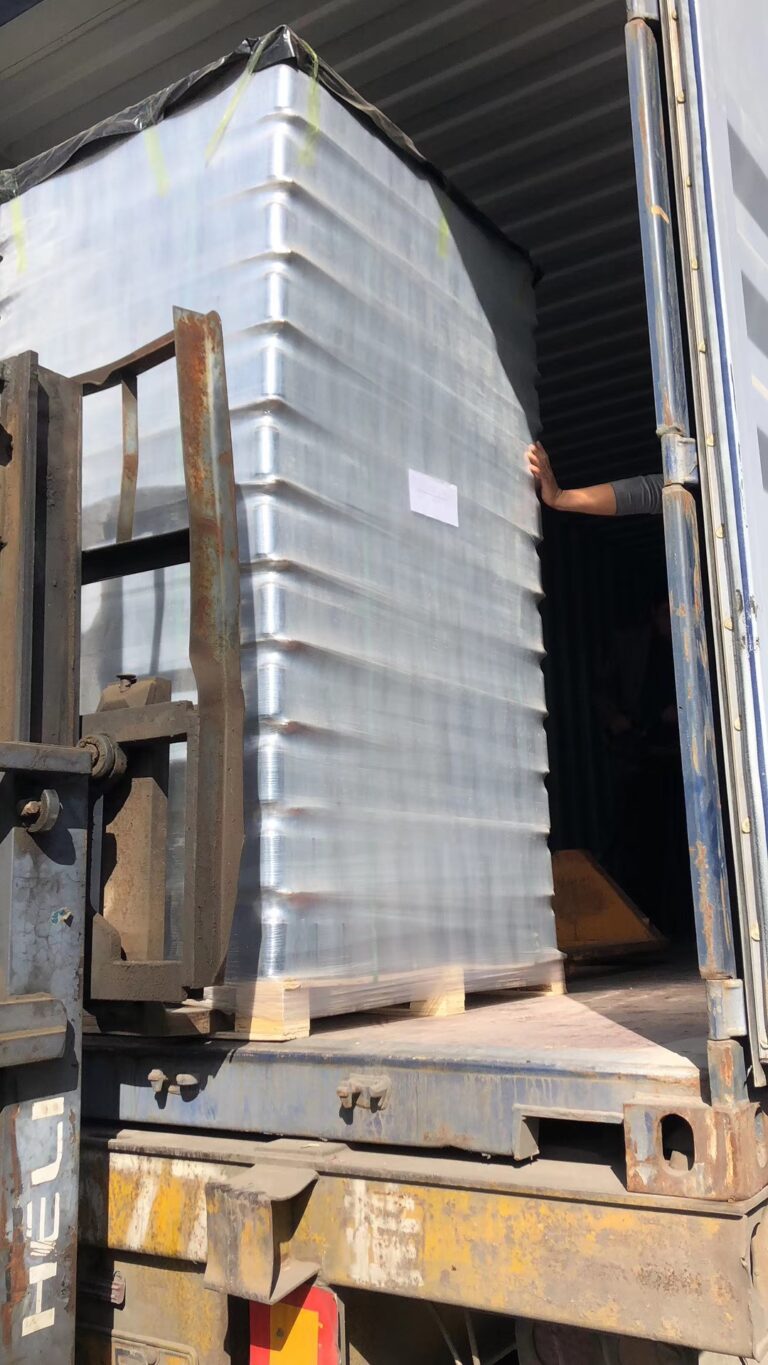 Forklift loading a pallet of glass bottle cartons into an export container