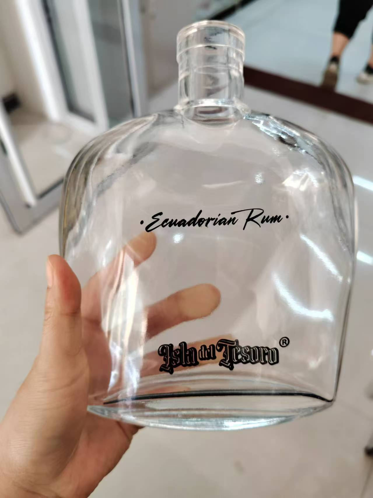 Black silk screen printed branding on a clear rum flask bottle